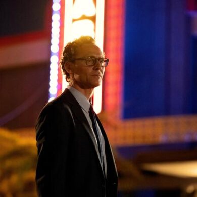 Tom Hiddleston steht vor einem Gebäude im Film "The Life of Chuck!.