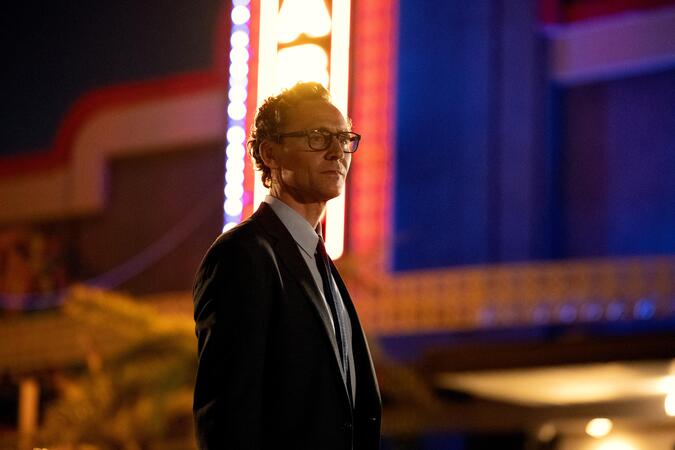 Tom Hiddleston steht vor einem Gebäude im Film "The Life of Chuck!.