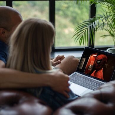 zwei Personen sitzen auf dem Sofa und schauen einen Film auf einem Laptop