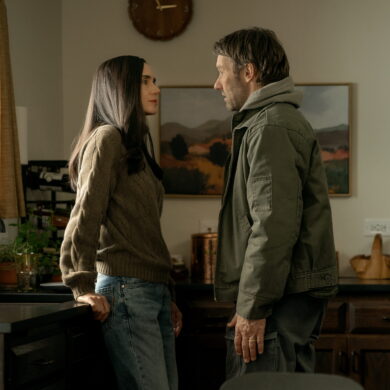 Eine FRau sitzt in einem Büro auf dem Schreibtisch. Ein Mann steht vor ihr.