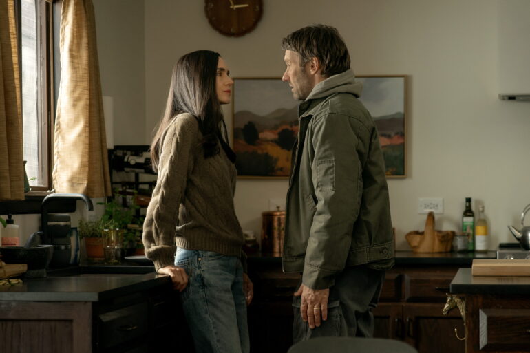 Eine FRau sitzt in einem Büro auf dem Schreibtisch. Ein Mann steht vor ihr.