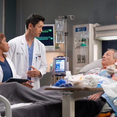 Zwei Arzte stehen am Krankenhausbett einer Patientin und reden.