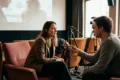 Photorealistische Szene eines intimen Regie-Interviews in einem modernen deutschen Kino: eine einzelne Regisseurin sitzt leicht seitlich vor der Leinwand, gegenüber ein Interviewer mit kleinem Mikrofon, im Hintergrund unscharf Kameratechnik und leere Kinositze. Natürliches warmes Licht, realistische Haut- und Stofftexturen, ruhige cineastische Stimmung in gedeckten Rot- und Brauntönen, keine Schrift, keine Logos, no text