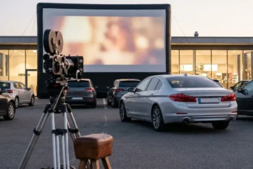 Fotorealistische Szene eines modernen Autokinos in Deutschland bei Abenddämmerung, mehrere Autos vor einer großen Leinwand, natürliches Licht, realistische Texturen auf Fahrzeugen, Asphalt und Himmel, stimmungsvolle Kinoatmosphäre, eine Option subtil als Top-Wahl visuell hervorgehoben durch Komposition und Lichtführung, hochwertig, sauber, ohne Text im Bild
