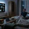 Fotorealistische Szene in einem gemütlichen deutschen Wohnzimmer bei natürlichem Abendlicht: genau 3 Personen sitzen auf einem Sofa vor einem modernen Fernseher, auf dem eine Streaming-Oberfläche ohne lesbaren Text zu sehen ist, dazu ein Tablet auf dem Couchtisch, Fernbedienung, Popcorn-Schale und weiche Decken mit realistischen Stofftexturen. Warme, natürliche Farben, glaubwürdige Hauttöne, feine Details bei Holz, Glas und Stoff, ruhige Heimkino-Stimmung mit Fokus auf legale Streaming-Nutzung, moderne Technik und entspanntes gemeinsames Filme-Schauen, ohne jegliche Schrift im Bild.