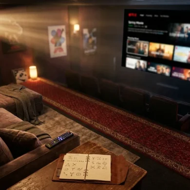 Fotorealistische Szene eines modernen Wohnzimmers mit großem Fernseher, auf dem eine Streaming-Auswahl mit Serienwelten angedeutet wird, daneben Fernbedienung, Notizbuch mit Watchlist und Sofa in warmer natürlicher Beleuchtung, realistische Texturen, dezente cineastische Atmosphäre, kein Text im Bild